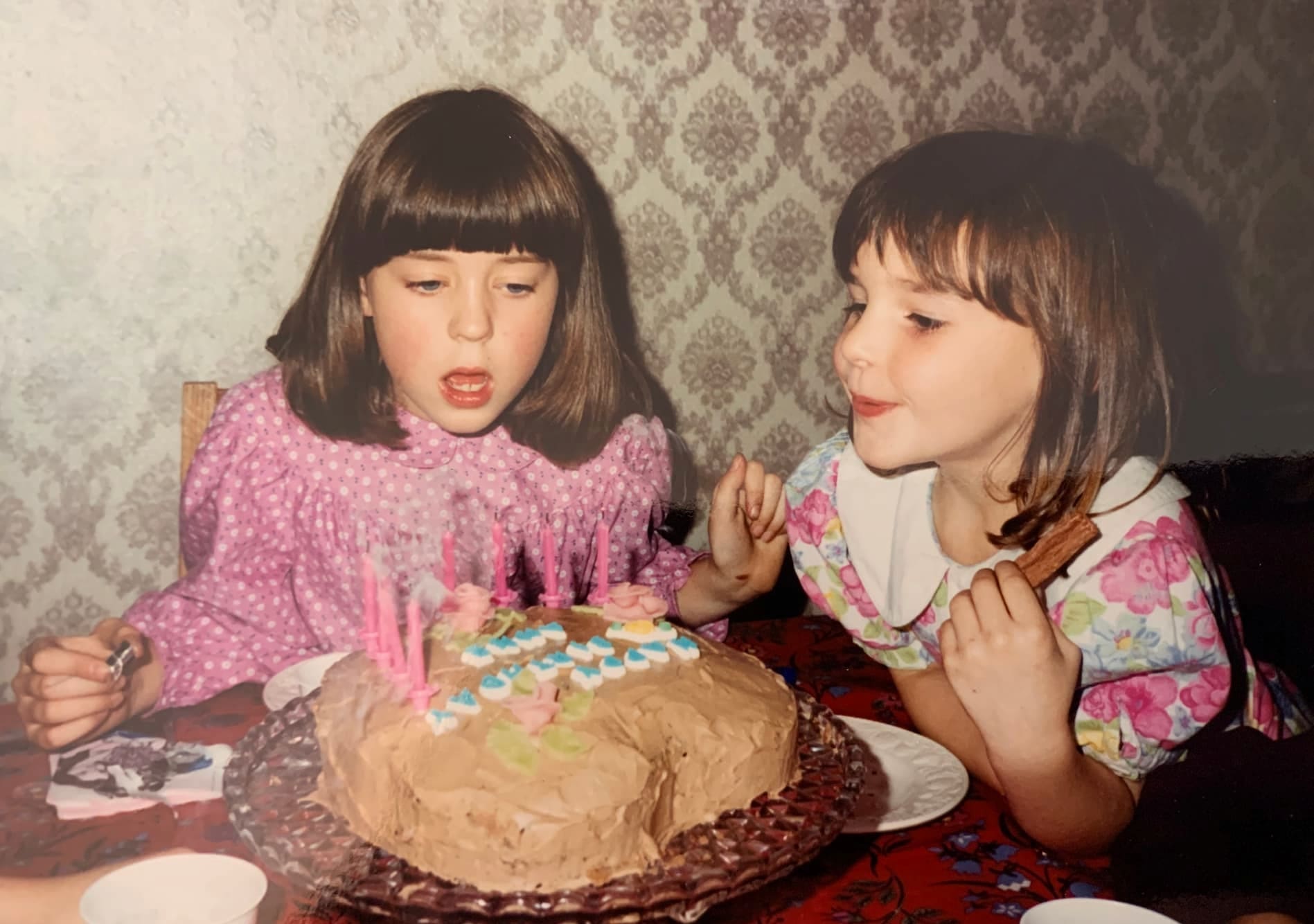 A photo of two girls with a birthday cake.